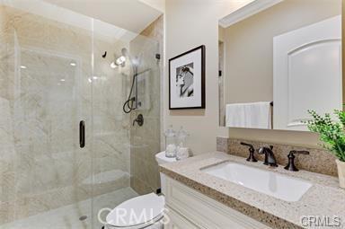 bathroom featuring vanity, toilet, and a shower with shower door