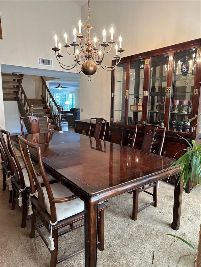 carpeted dining space featuring stairs, visible vents, and a ceiling fan