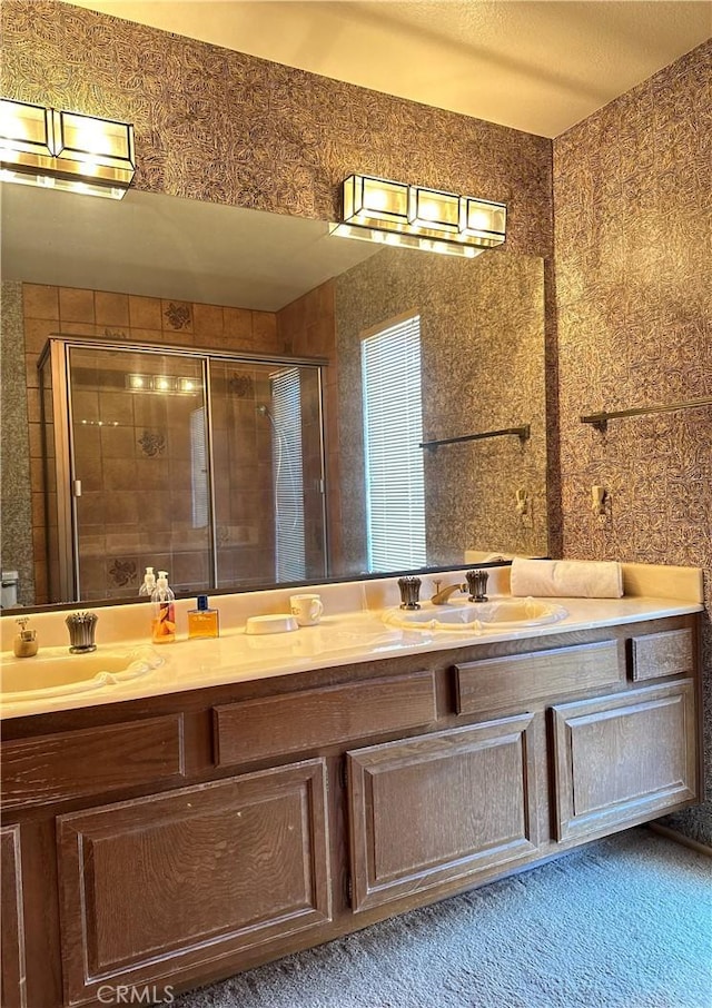 bathroom featuring a stall shower, a sink, and double vanity