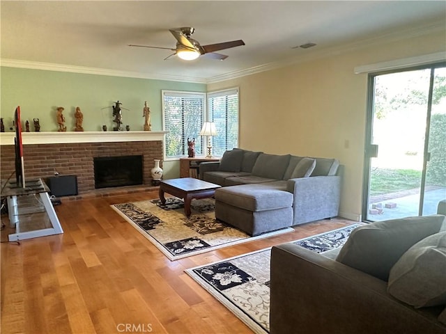 living room with ceiling fan, plenty of natural light, crown molding, and wood finished floors