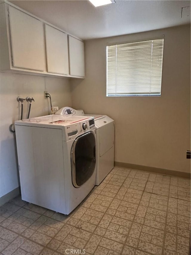 washroom featuring light floors, cabinet space, washing machine and clothes dryer, and baseboards