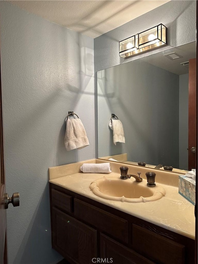 bathroom with a textured wall and vanity