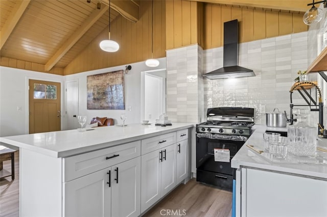 kitchen with pendant lighting, black range with gas cooktop, white cabinetry, lofted ceiling with beams, and wall chimney exhaust hood