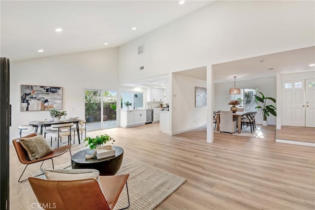 living room featuring high vaulted ceiling, light hardwood / wood-style floors, and sink