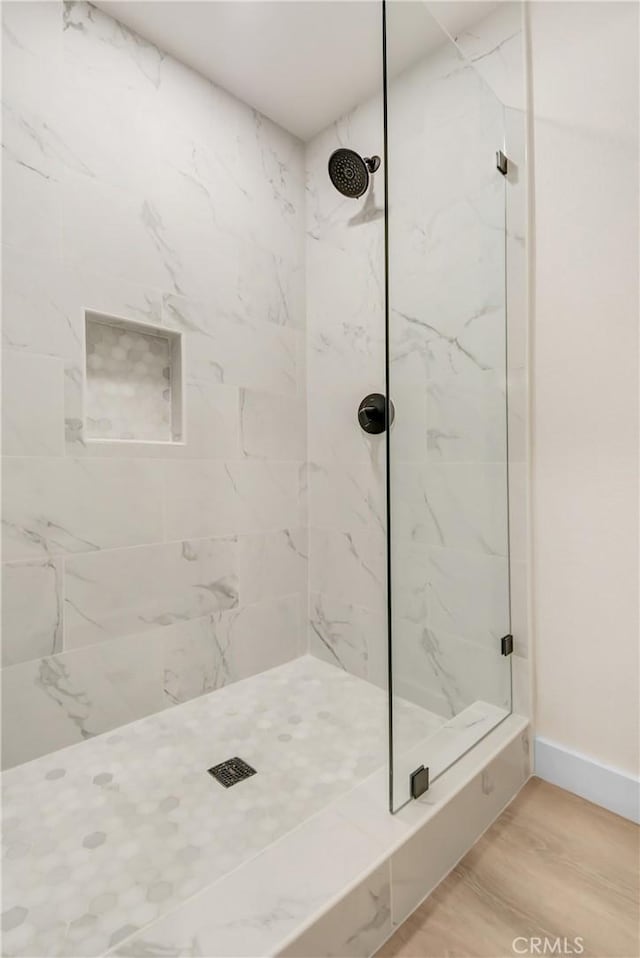 bathroom featuring hardwood / wood-style floors and a tile shower