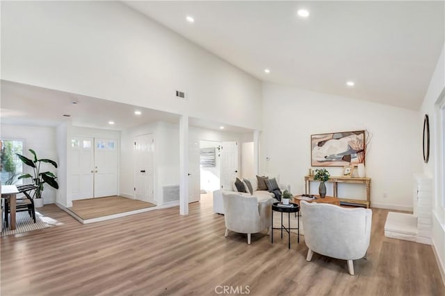 living room featuring high vaulted ceiling and light wood-type flooring