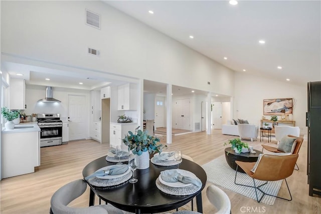 dining space with light hardwood / wood-style flooring and high vaulted ceiling