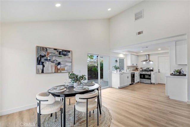 dining area featuring sink, a high ceiling, and light wood-type flooring