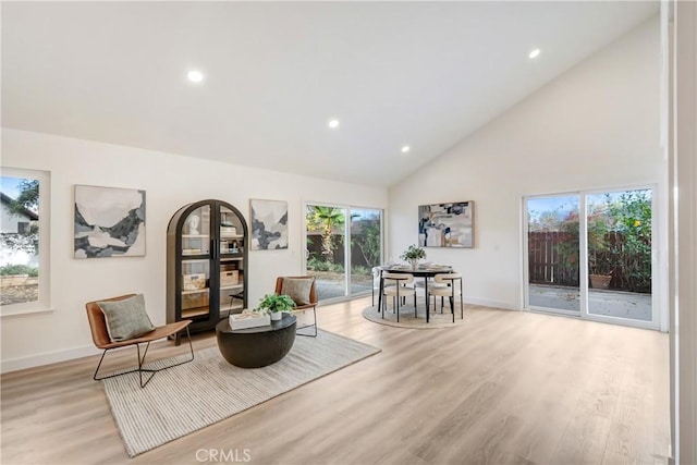 sitting room with high vaulted ceiling and light hardwood / wood-style floors