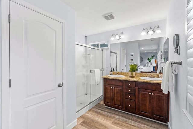 bathroom featuring wood-type flooring, an enclosed shower, and vanity