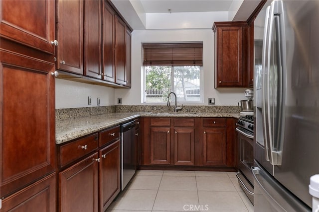 kitchen featuring appliances with stainless steel finishes, light stone countertops, sink, and light tile patterned floors