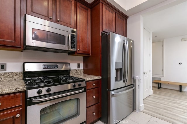 kitchen featuring stainless steel appliances, light stone counters, and light hardwood / wood-style floors