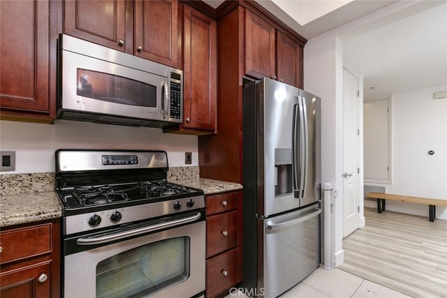 1023 Wilcox Ave Unit 102, Los Angeles, CA 90038 - kitchen featuring appliances with stainless steel finishes, light stone countertops, and light tile patterned floors