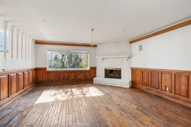 unfurnished living room with a brick fireplace, crown molding, and wood-type flooring