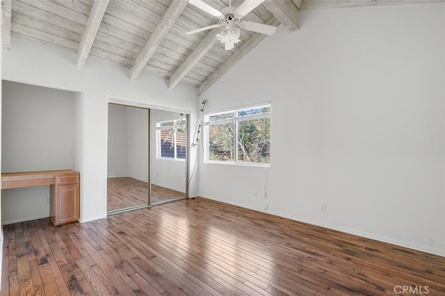 unfurnished bedroom featuring vaulted ceiling with beams, built in desk, dark hardwood / wood-style flooring, a closet, and ceiling fan