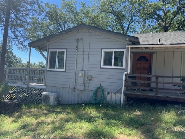 view of property exterior featuring a wooden deck, ac unit, and a yard