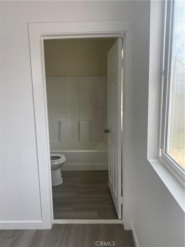 bathroom featuring hardwood / wood-style floors, shower / bathtub combination, and toilet