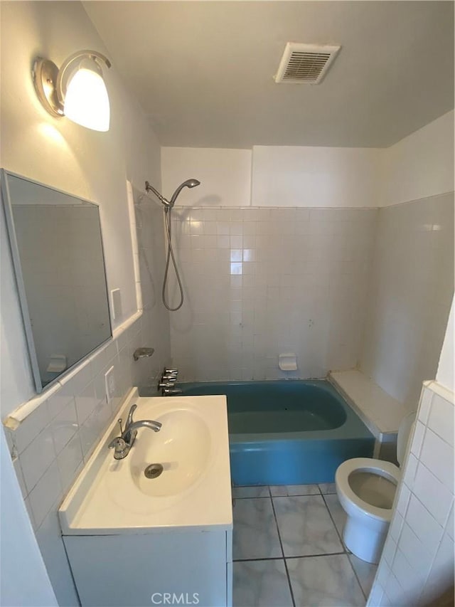 full bathroom with sink, tile walls, tiled shower / bath, decorative backsplash, and toilet