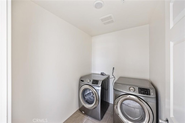 laundry room featuring washer and dryer and light tile patterned floors