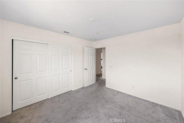 unfurnished bedroom featuring light colored carpet and a closet