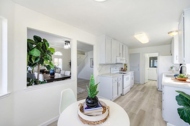 kitchen featuring white cabinetry, white appliances, light hardwood / wood-style floors, and sink