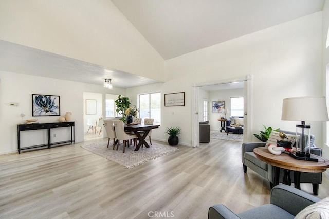 dining area featuring high vaulted ceiling and light hardwood / wood-style floors