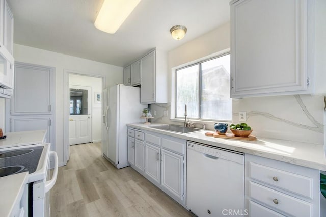 kitchen with white cabinetry, sink, white appliances, and light wood-type flooring