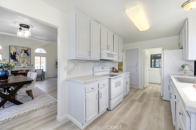 kitchen featuring sink, backsplash, white cabinets, white appliances, and light hardwood / wood-style flooring