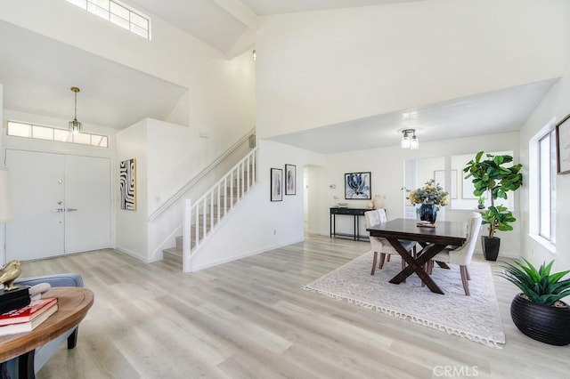 entryway featuring high vaulted ceiling, light hardwood / wood-style floors, and beamed ceiling