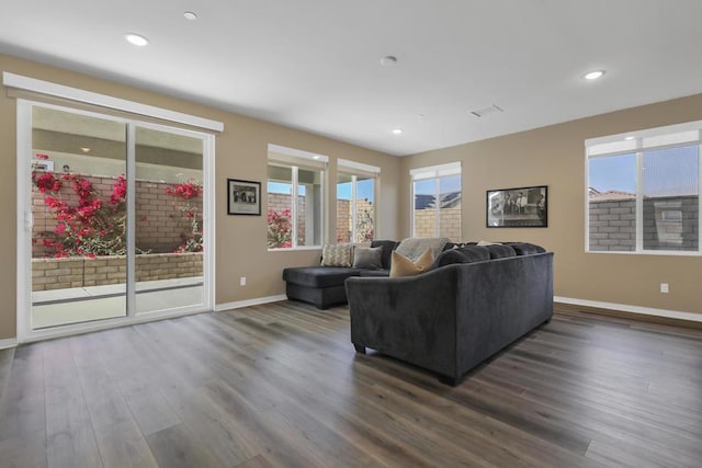 living room with dark wood-type flooring and a healthy amount of sunlight