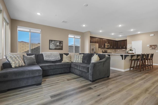 living room with plenty of natural light, sink, and light hardwood / wood-style floors