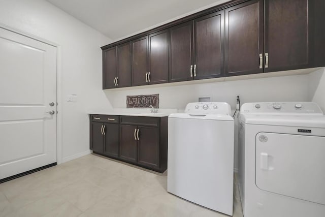 clothes washing area featuring cabinets, sink, and independent washer and dryer