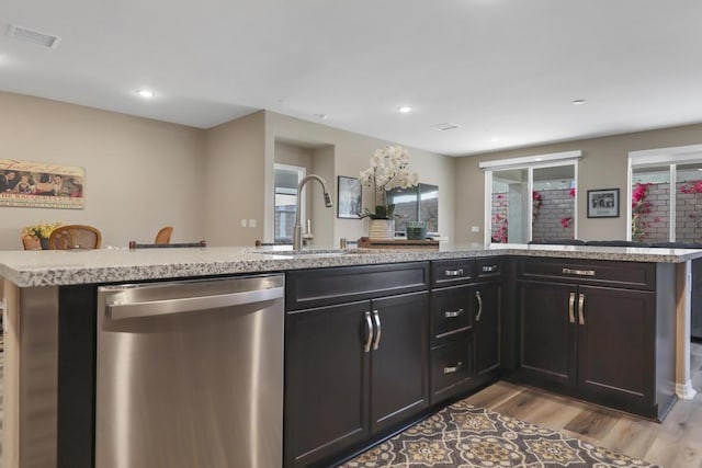 kitchen featuring stainless steel dishwasher, sink, and light wood-type flooring