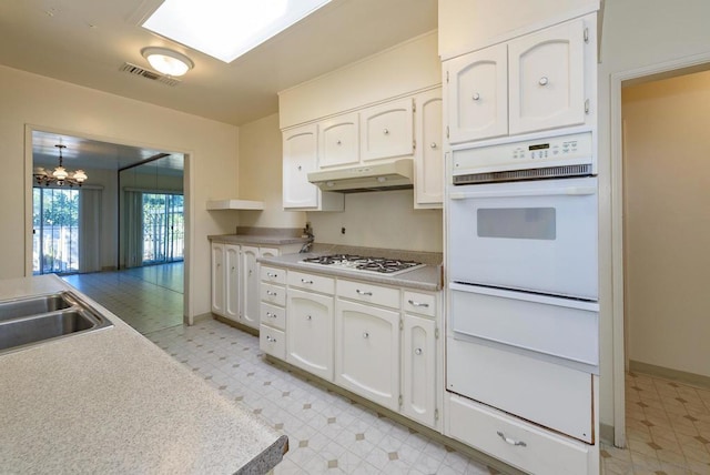 kitchen featuring sink, a chandelier, white cabinets, and white appliances