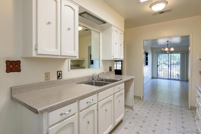 kitchen featuring white cabinetry, sink, hanging light fixtures, and an inviting chandelier