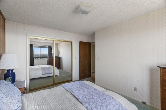 carpeted bedroom featuring wallpapered walls, a textured ceiling, and a closet