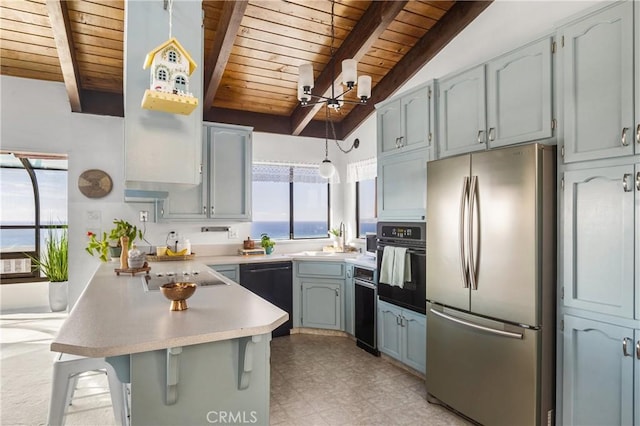 kitchen with a breakfast bar, a peninsula, light countertops, black appliances, and a sink