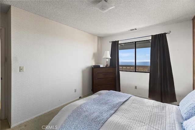 bedroom with carpet, visible vents, a textured ceiling, baseboards, and wallpapered walls