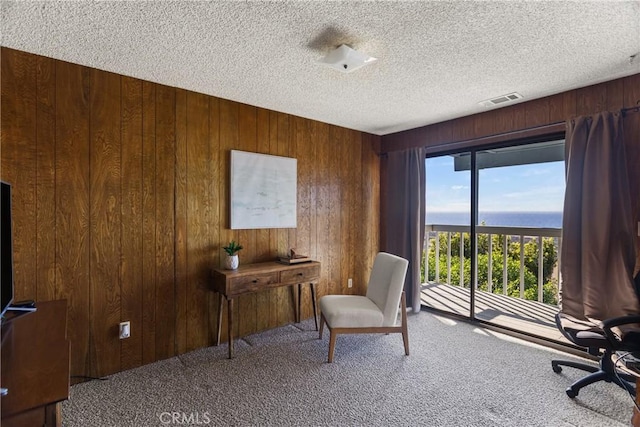 carpeted office space with wood walls, visible vents, and a textured ceiling