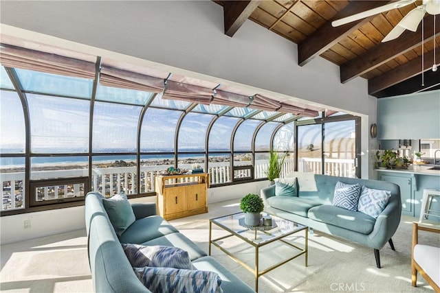 sunroom featuring lofted ceiling with beams, wooden ceiling, a water view, a sink, and a ceiling fan