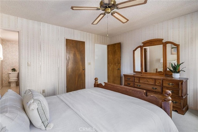 bedroom with carpet floors, a textured ceiling, ensuite bathroom, and wallpapered walls