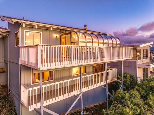 back house at dusk with a balcony