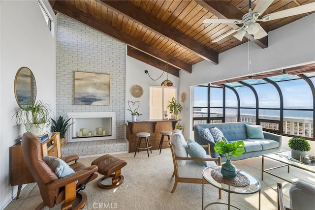 sunroom / solarium featuring lofted ceiling with beams, ceiling fan, a water view, wooden ceiling, and a brick fireplace