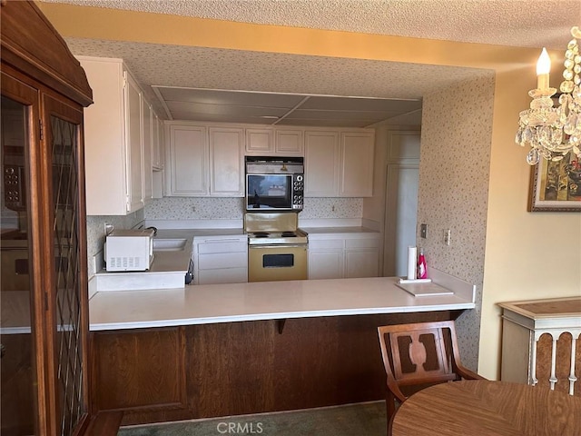 kitchen with range with electric cooktop, sink, a kitchen bar, and kitchen peninsula