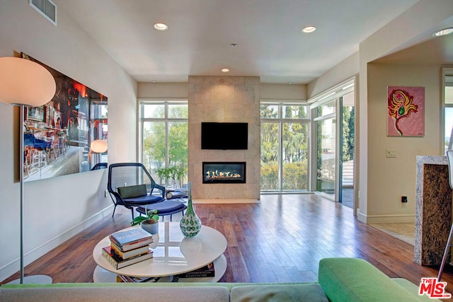 living room with a tiled fireplace and hardwood / wood-style flooring