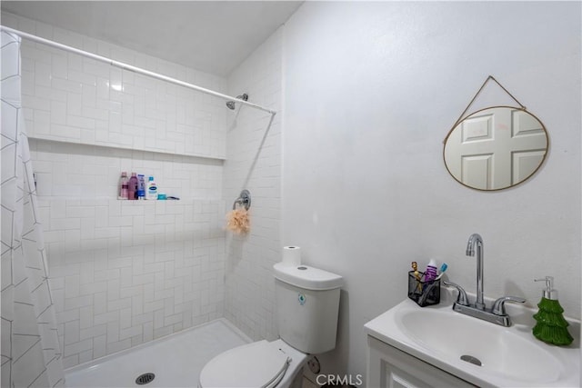 bathroom featuring vanity, toilet, and a tile shower