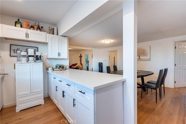 kitchen with white cabinetry, light wood-type flooring, and kitchen peninsula