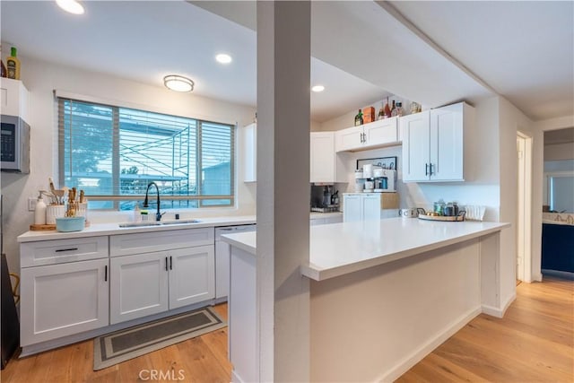 kitchen with white cabinetry, kitchen peninsula, sink, and light wood-type flooring