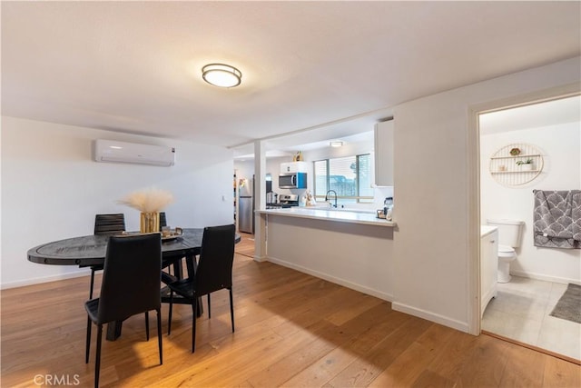 dining space featuring sink, light hardwood / wood-style floors, and a wall mounted AC