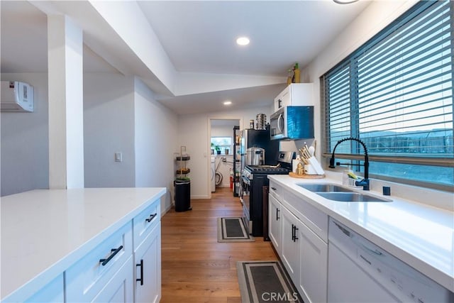 kitchen featuring appliances with stainless steel finishes, sink, hardwood / wood-style floors, and white cabinets